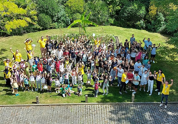 緑の芝生の校庭で手を降るながら集合写真